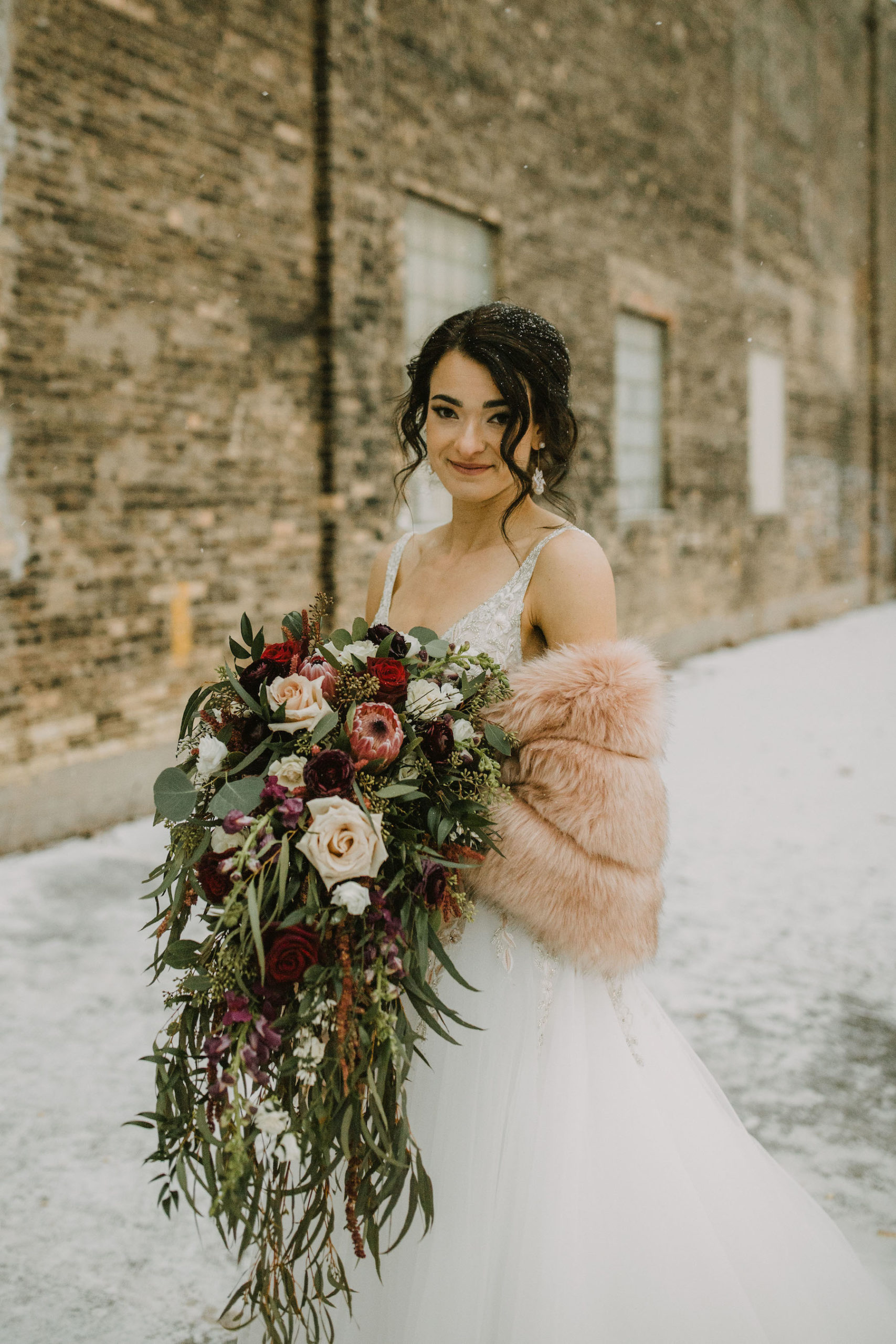 Milwaukee bride in downtown Milwaukee in Winter looking at the camera with a soft smile holding her bouquet. 