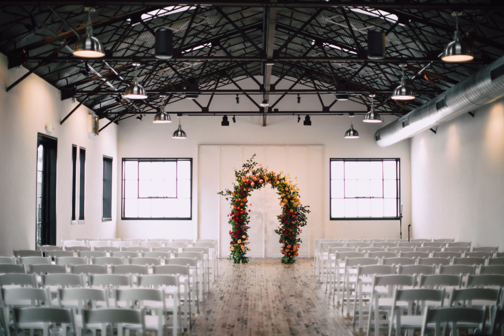 Wedding ceremony setup at The Tinsmith Madison with a floral arch at the end of the aisle.