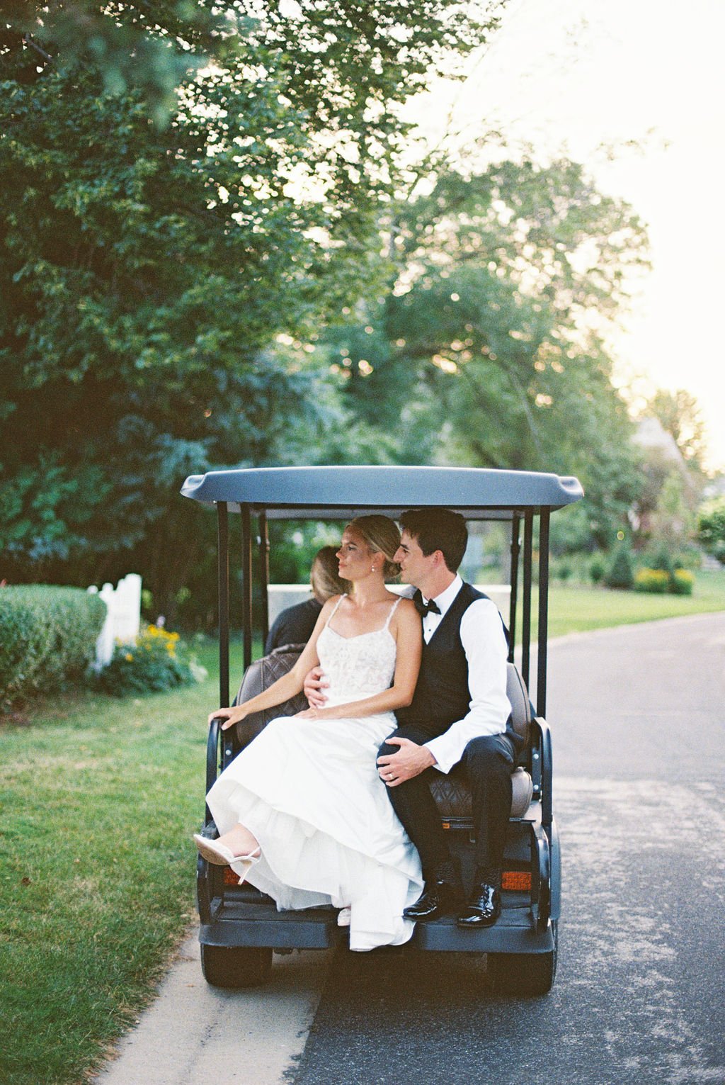 Bride and groom riding in a golf cart at their dream outdoor wedding venue