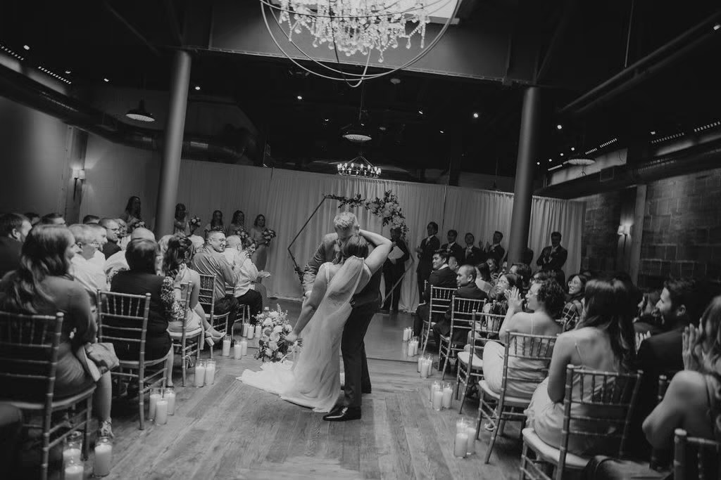 First kiss at indoor wedding venue in front of alter 