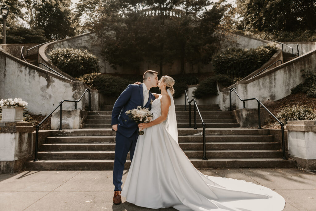 bride and groom kissing infront of a historic mansion staircase at their lake geneva wedding