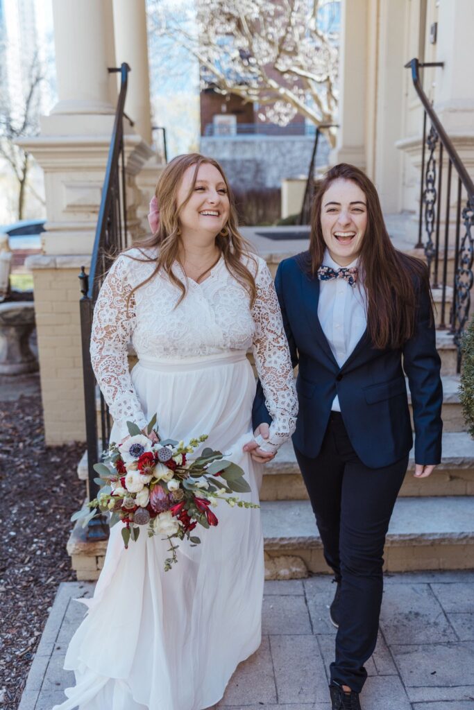 brides laughing while walking down the stairs at their lake geneva wedding 