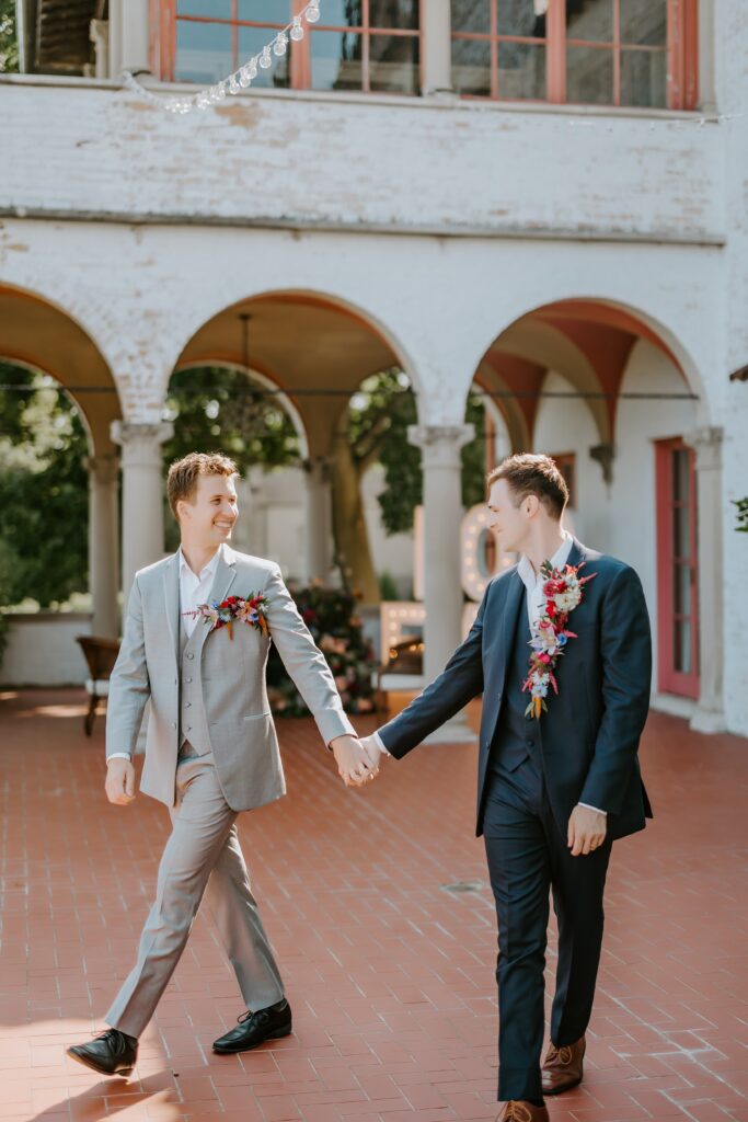 grooms walking hand-in-hand during their portrait shoot at their lake geneva wedding