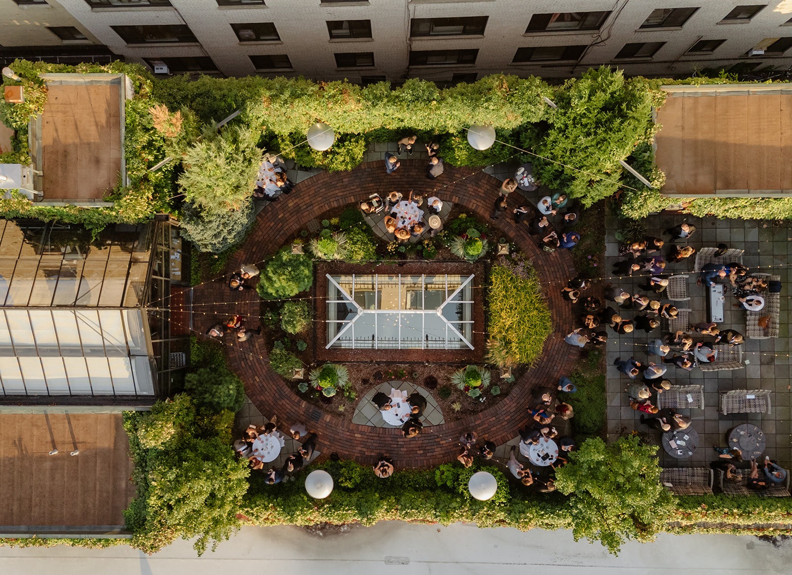 Aerial view of an outdoor wedding reception with guests mingling around cocktail tables in a lush courtyard at one of the most unique wedding reception venues in Madison WI