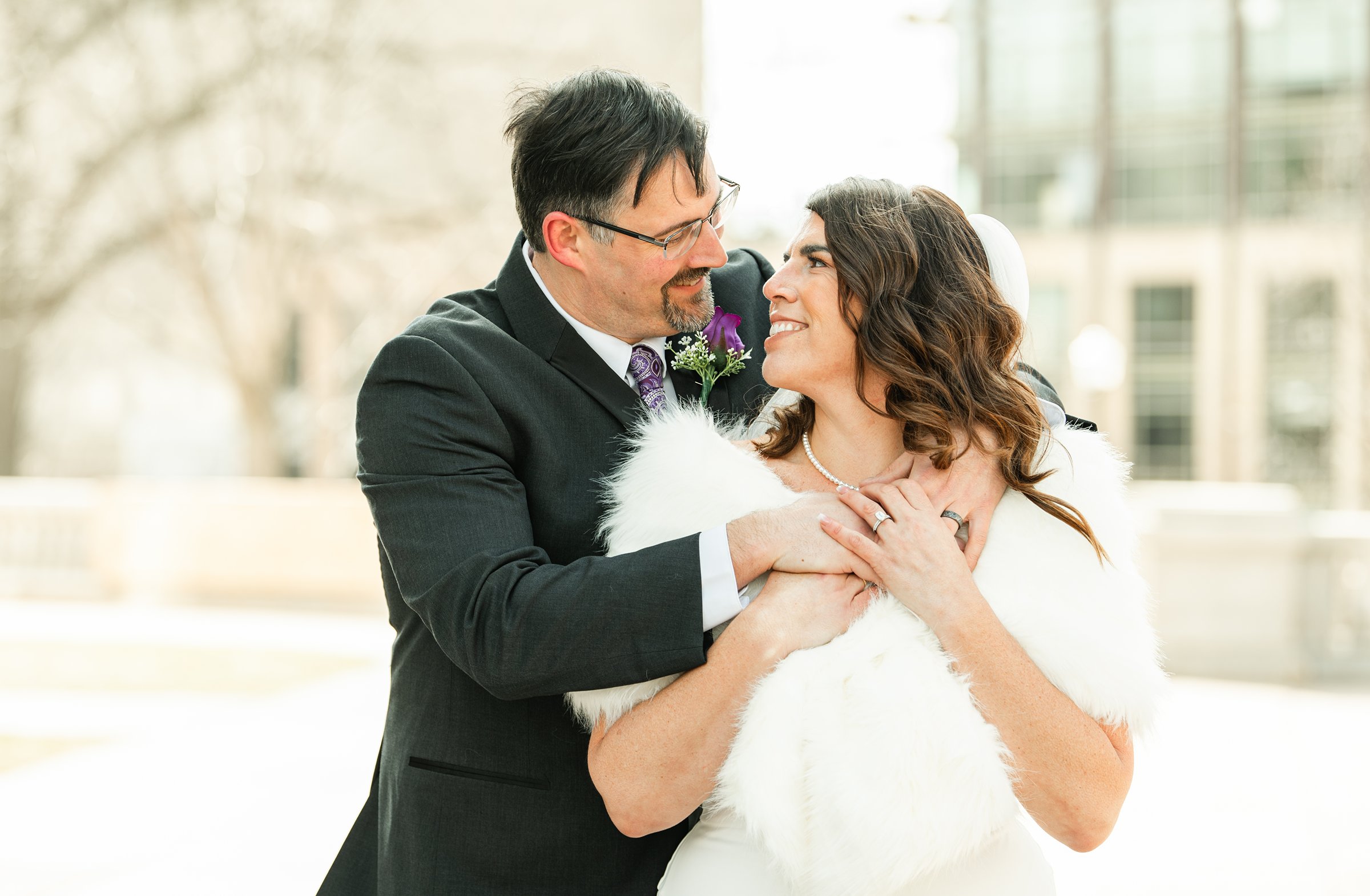 Groom holding the bride from behind as she smiles up at him during an outdoor wedding portrait at a Madison WI wedding venue