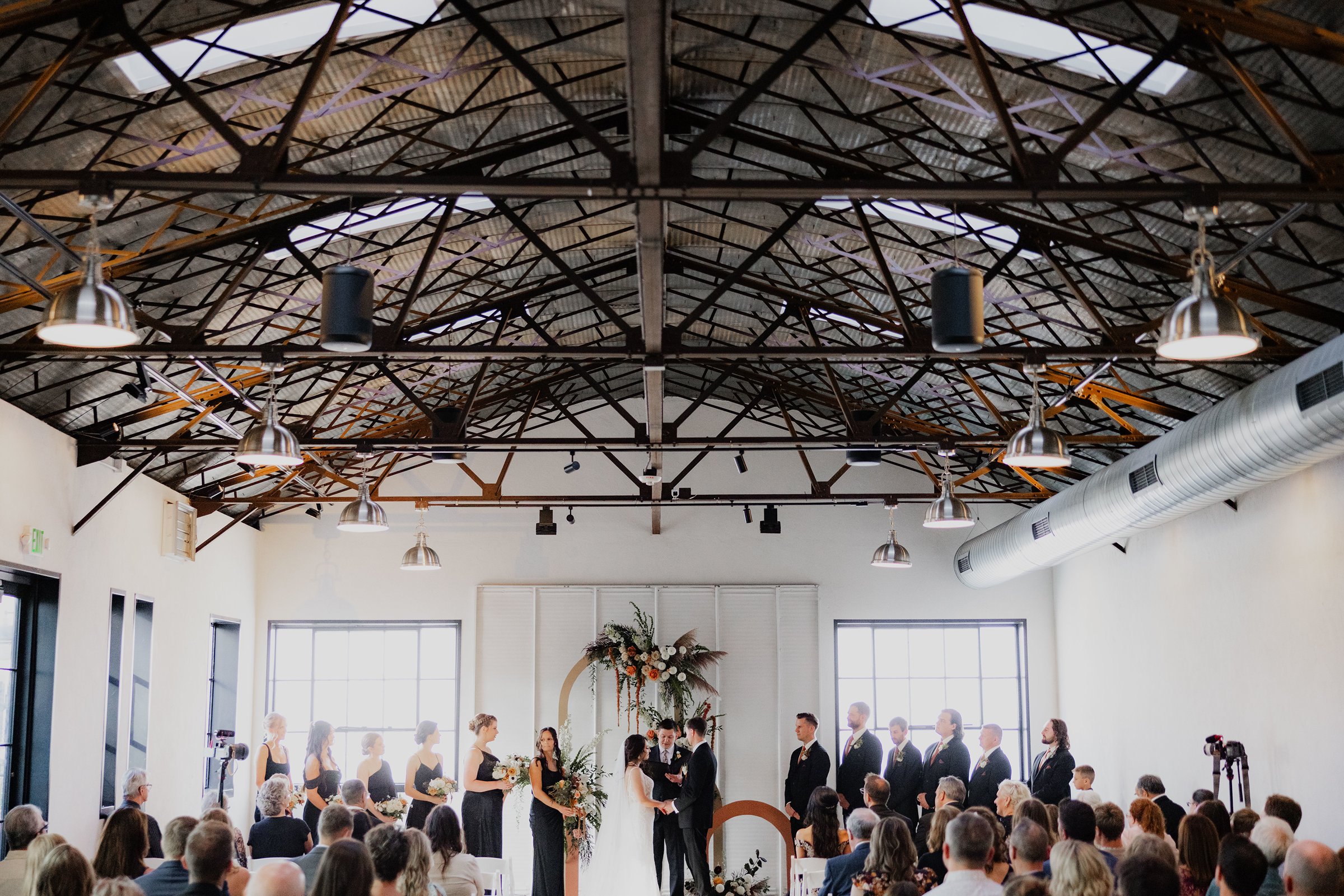 Indoor wedding ceremony with guests seated beneath exposed beams at one of the most popular Madison wedding venues