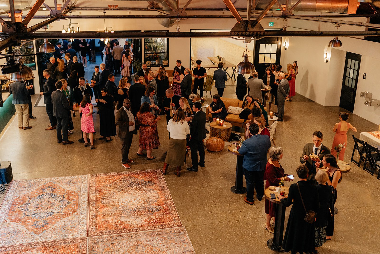 Guests mingling and dancing inside a spacious industrial-style reception venue, capturing the lively atmosphere of weddings Madison WI and popular places to get married in Madison WI.