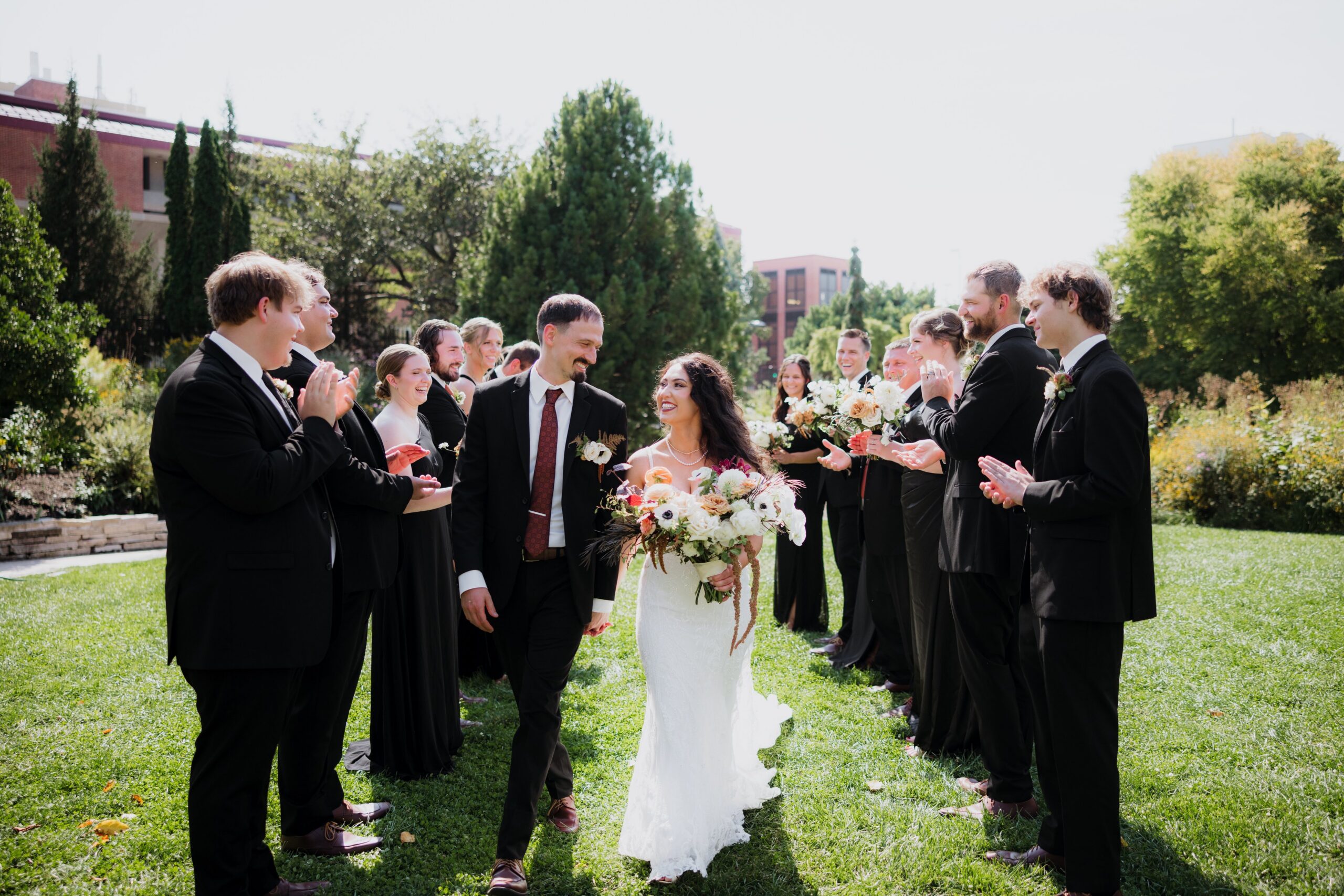 Bride and groom walking through a joyful wedding party lineup outdoors, capturing a celebratory moment from weddings Madison WI and beautiful places to get married in Madison WI.