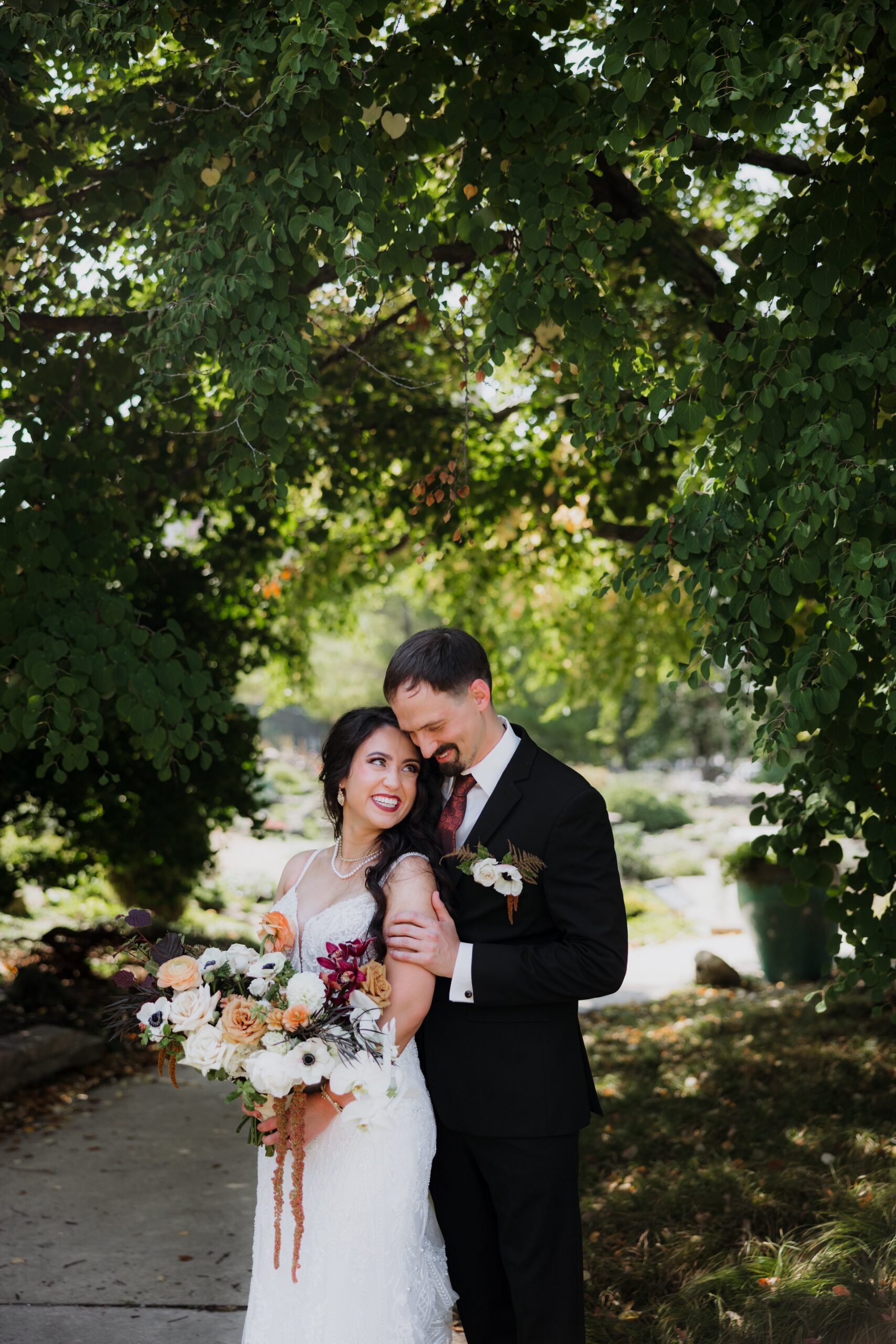 Bride and groom standing together on a shaded tree-lined path, capturing a romantic portrait from weddings Madison WI and beautiful outdoor places to get married in Madison WI.